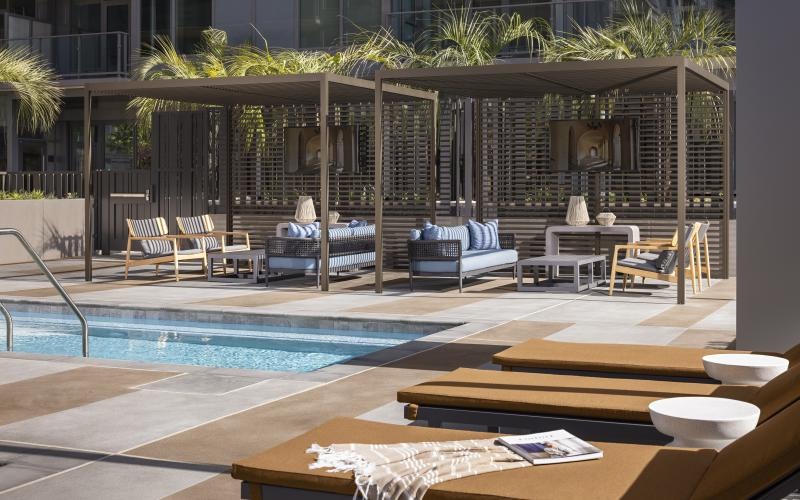 a pool with lounge chairs and a deck with a building in the background