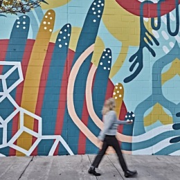 a person walking in front of a mural