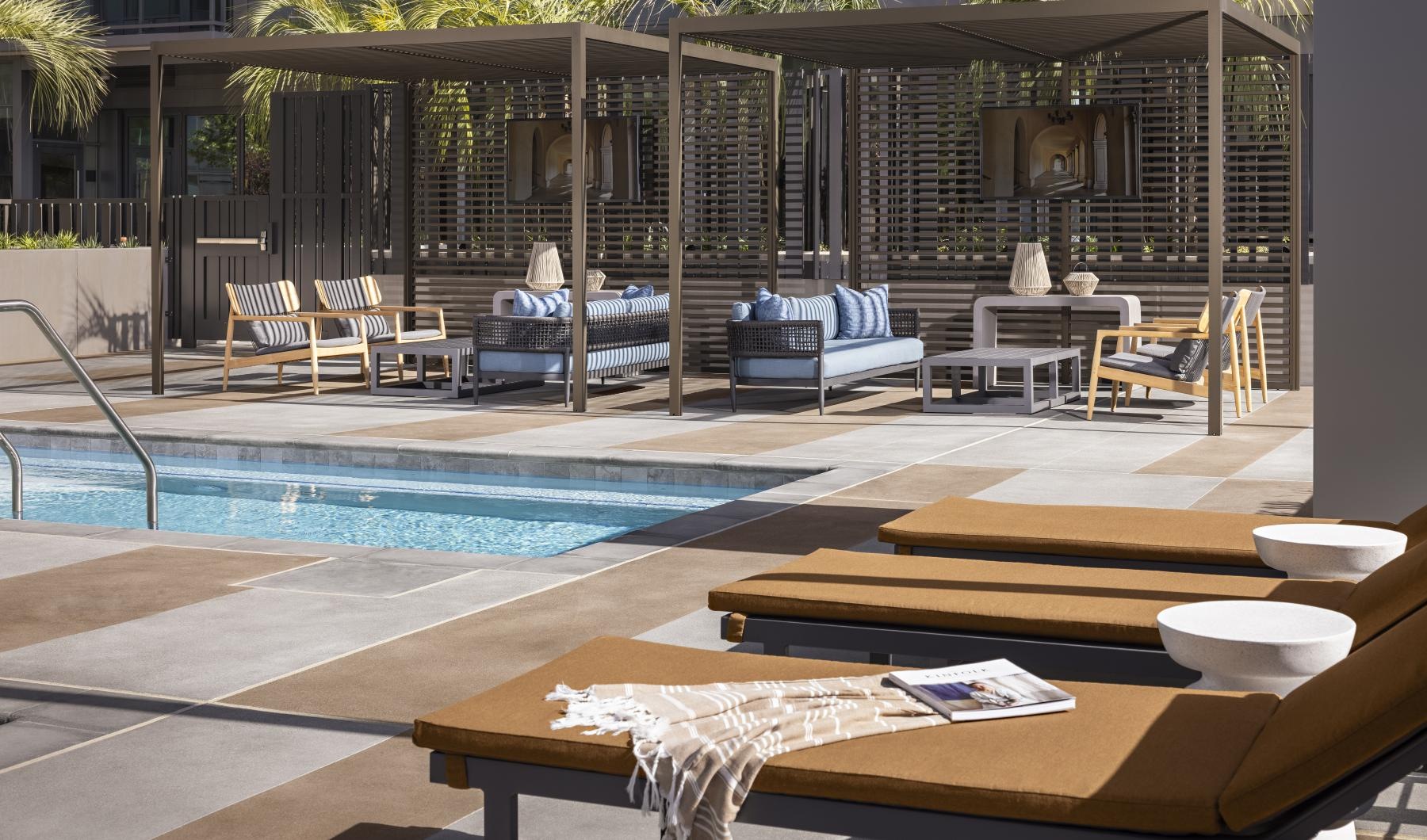a pool with lounge chairs and a deck with a building in the background